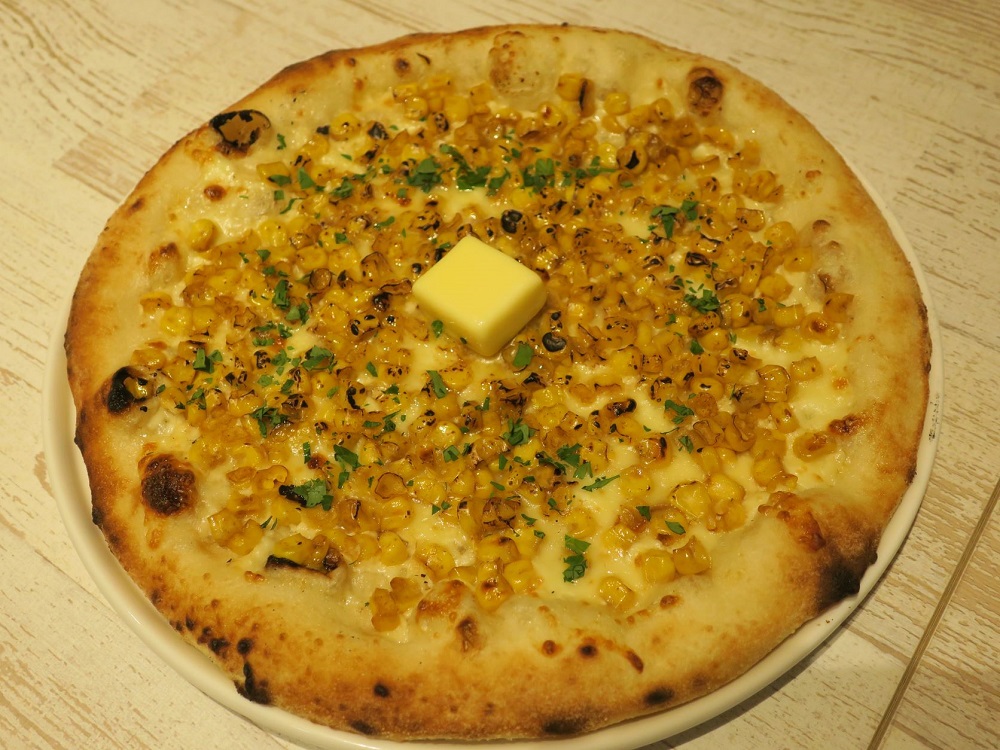 「北国とミルク」のメニューで北海道トウモロコシをたっぷりとのせた「北海道とうもろこし焦がし醤油バターピザ」1280円（税込）